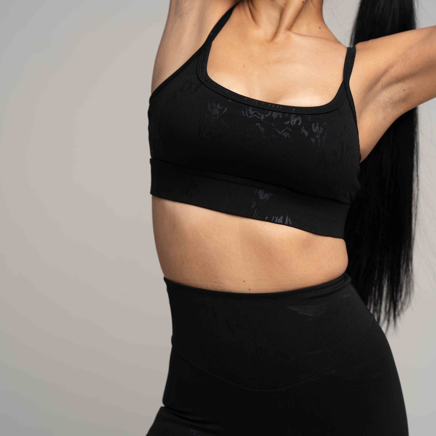 Person wearing a black sports bra and leggings against a neutral background