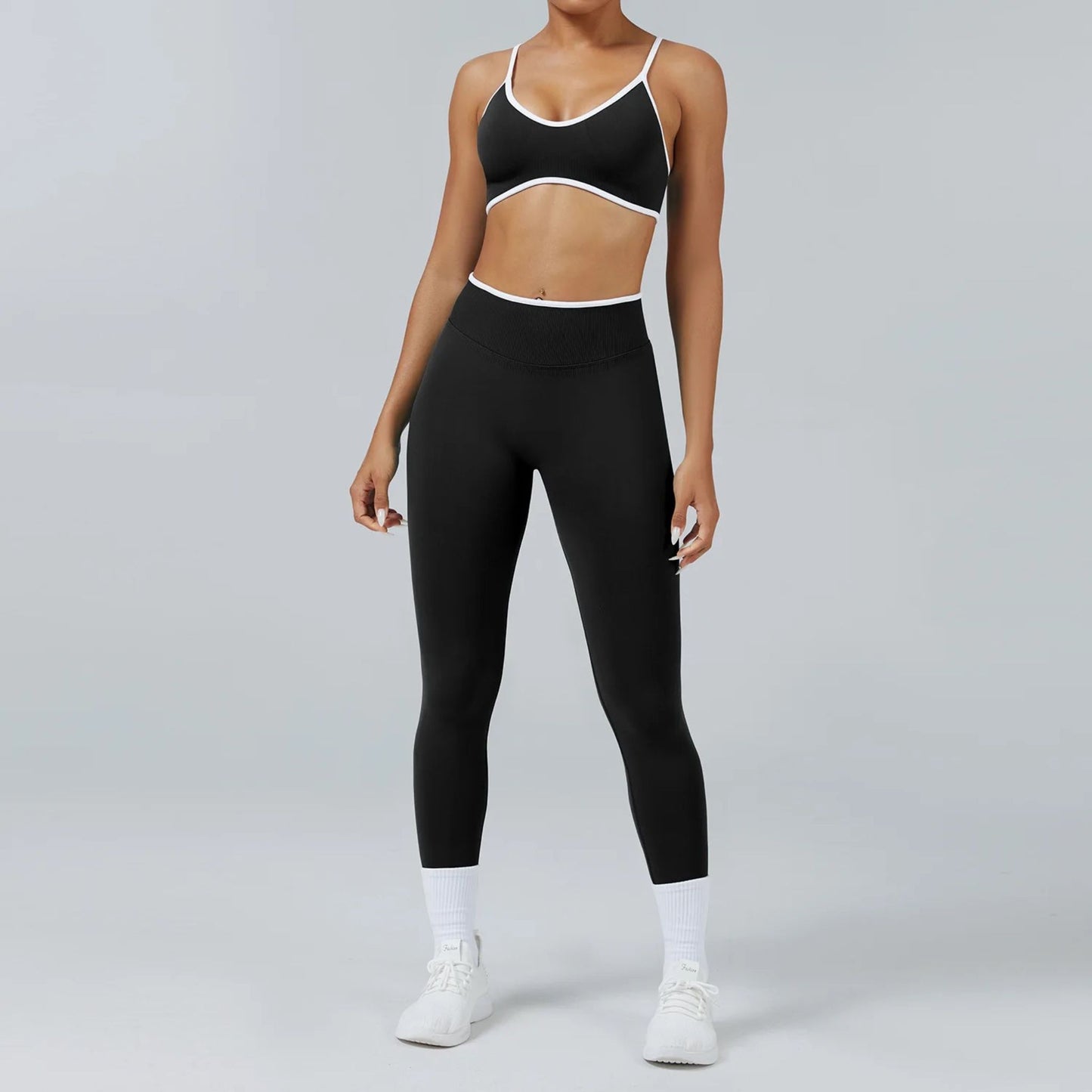 women wearing a 2 piece black workout set with white trim and white sneakers