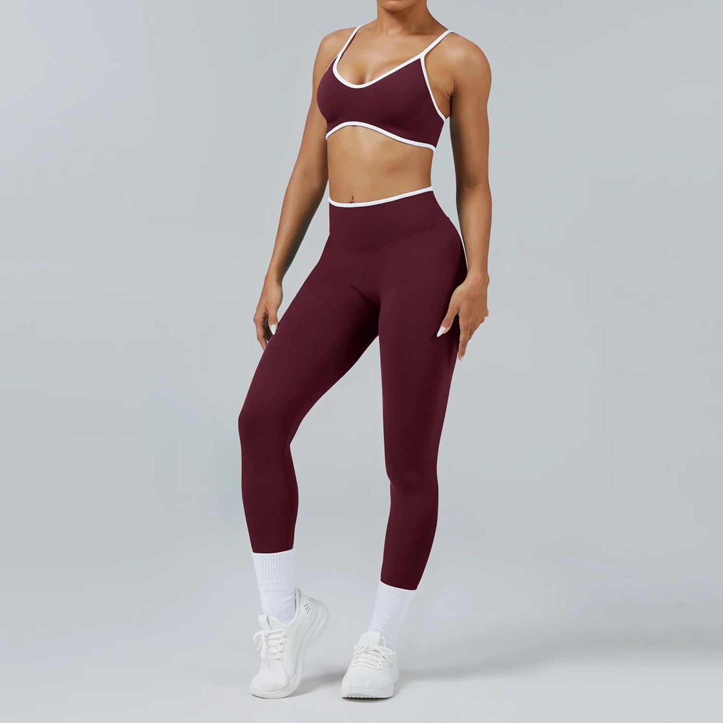 Person wearing burgundy athletic leggings and sports bra on a gray background