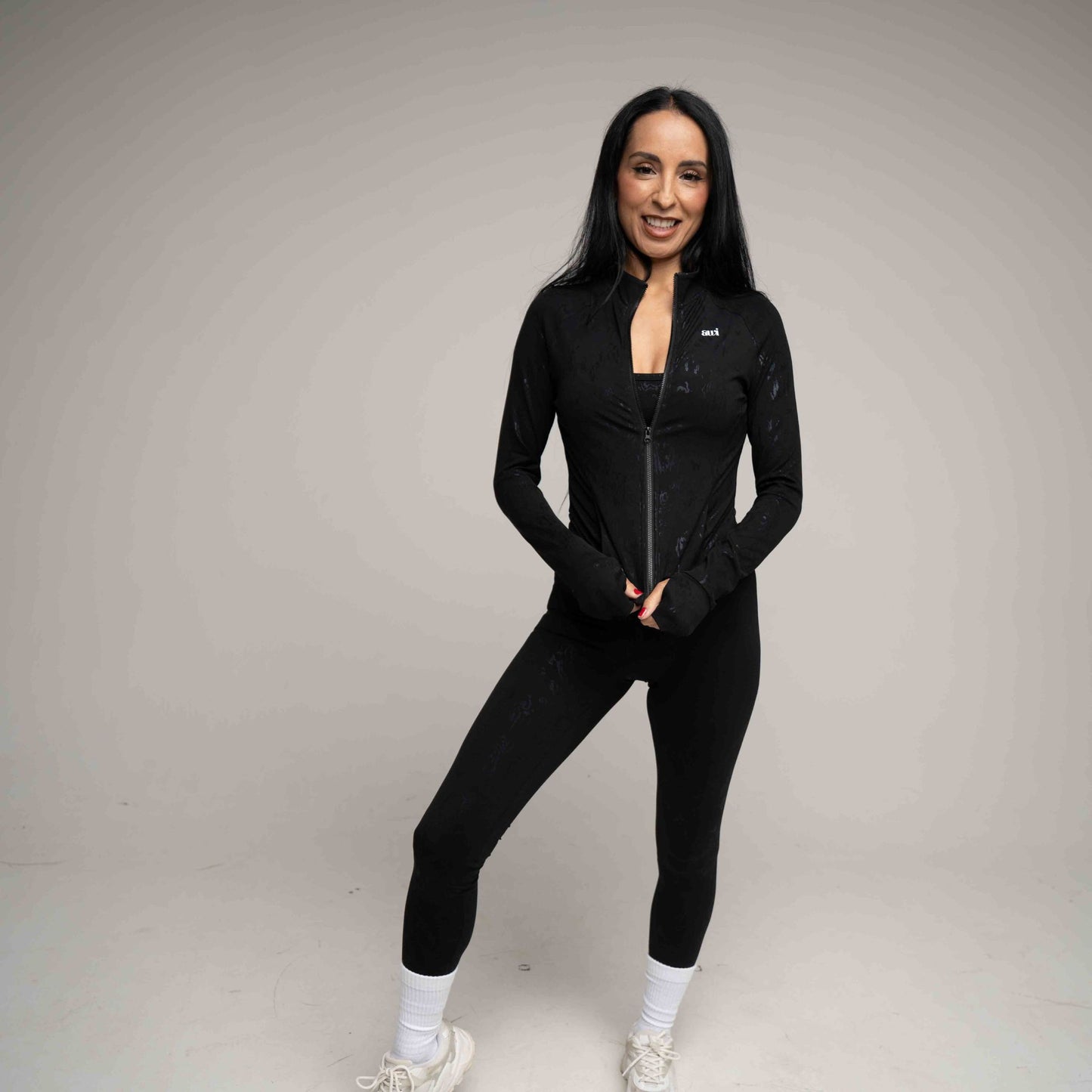 Woman wearing a black athletic outfit on a gray background