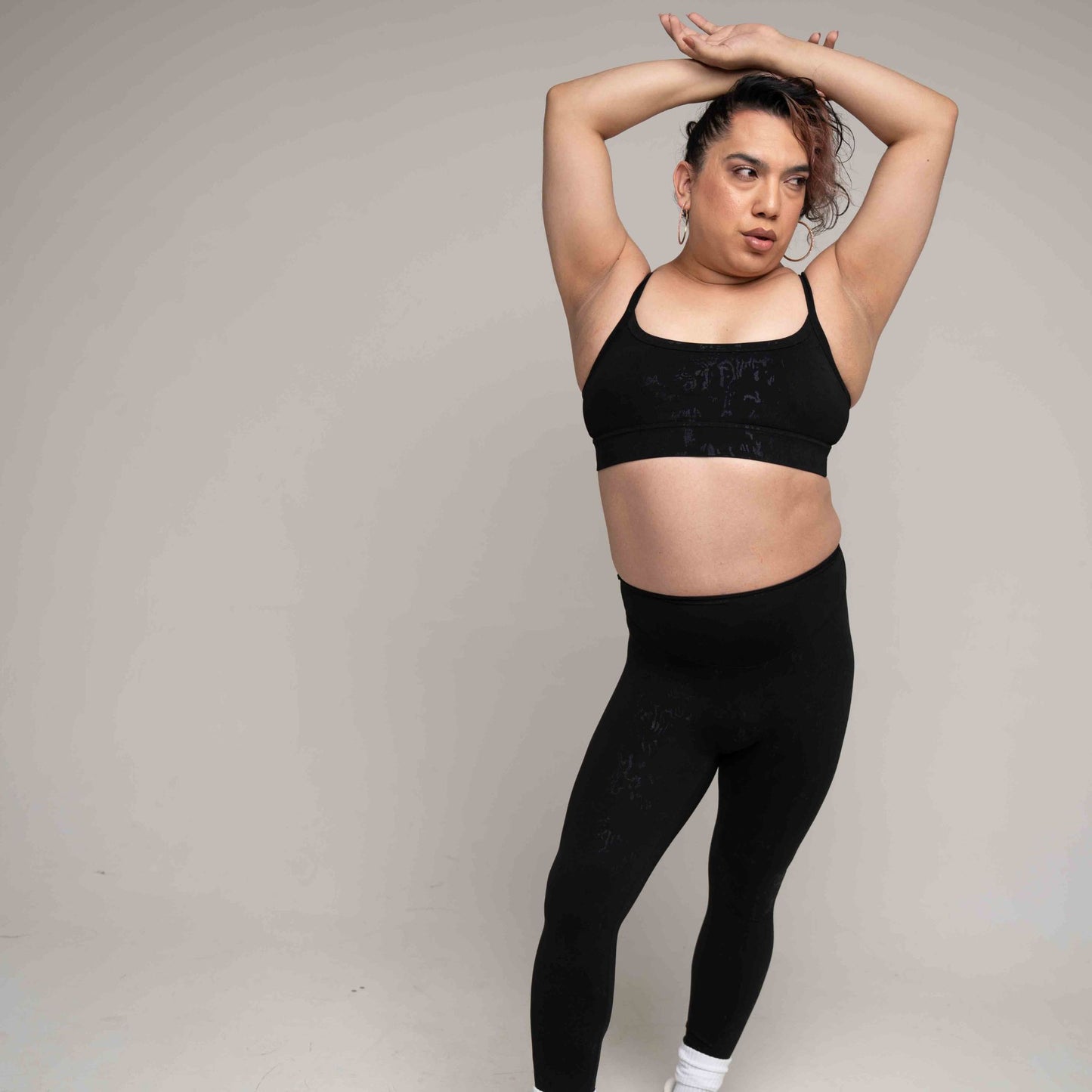 Person wearing a black sports bra and leggings against a plain background