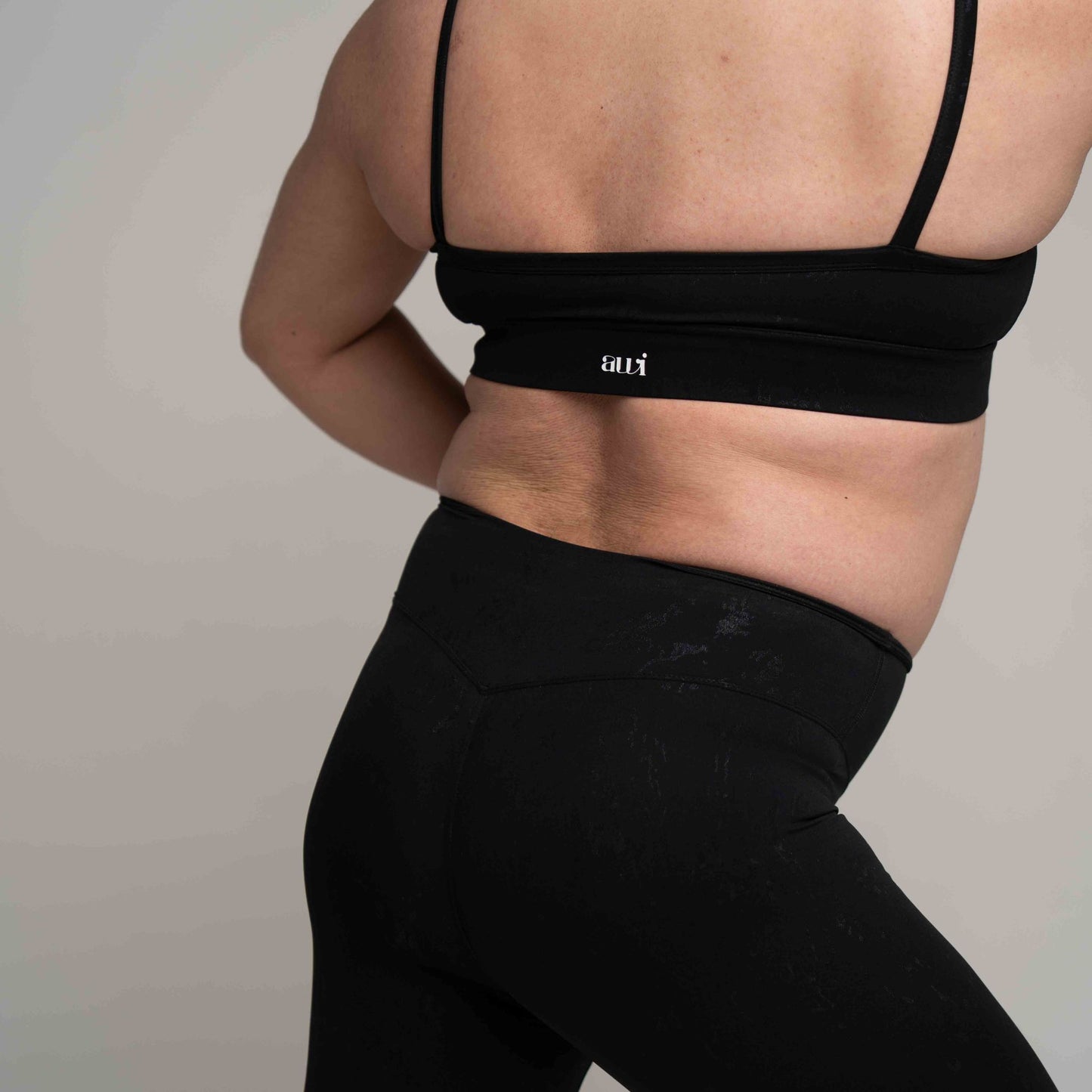 Person wearing a black sports bra and leggings on a plain background