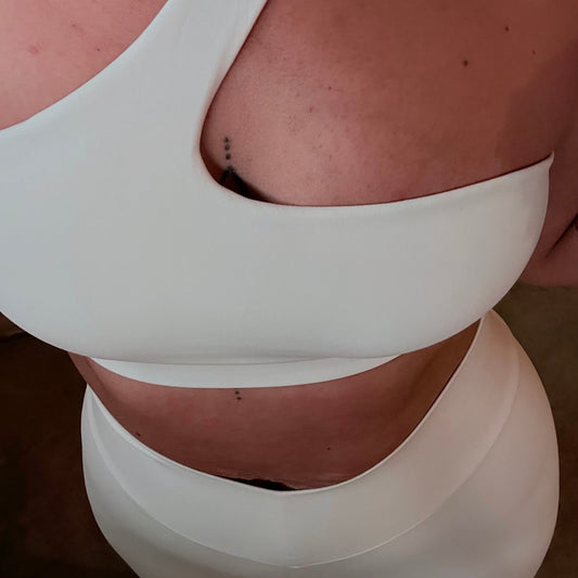 Model wearing Bare Intentions one-shoulder sports bra and scrunch leggings set by avvi in soft beige sculpted minimalist activewear.