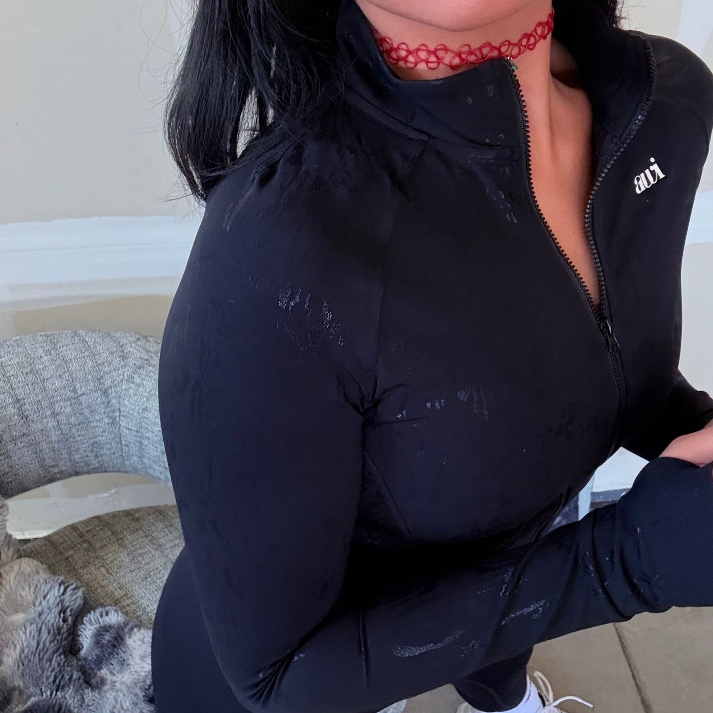Close-up of woman wearing black zip-up performance jacket by Avvi, paired with matching leggings.