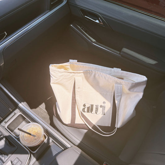 Avvi canvas tote bag on car seat next to iced coffee — ready for errands, workdays, or lounging