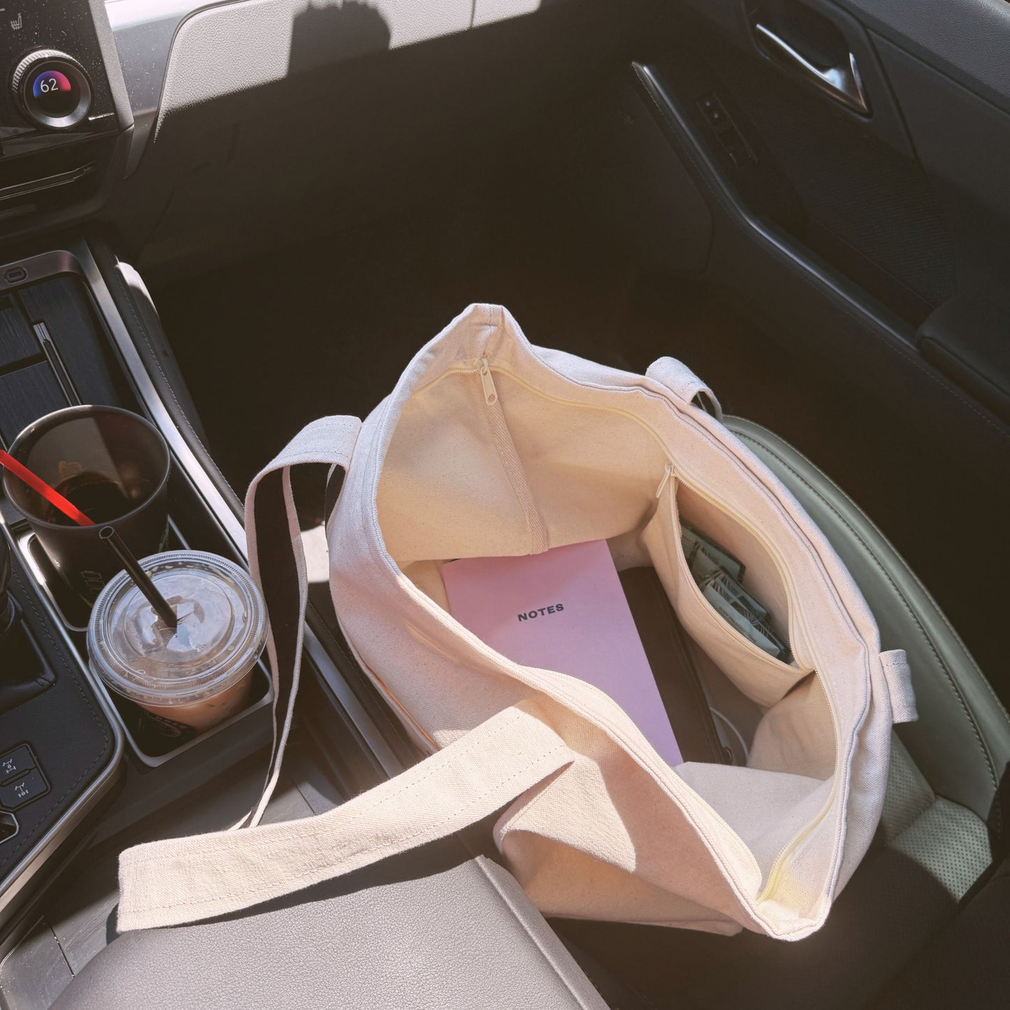 Inside view of Avvi canvas tote showing pink notebook, wallet, and everyday items — functional and spacious interior