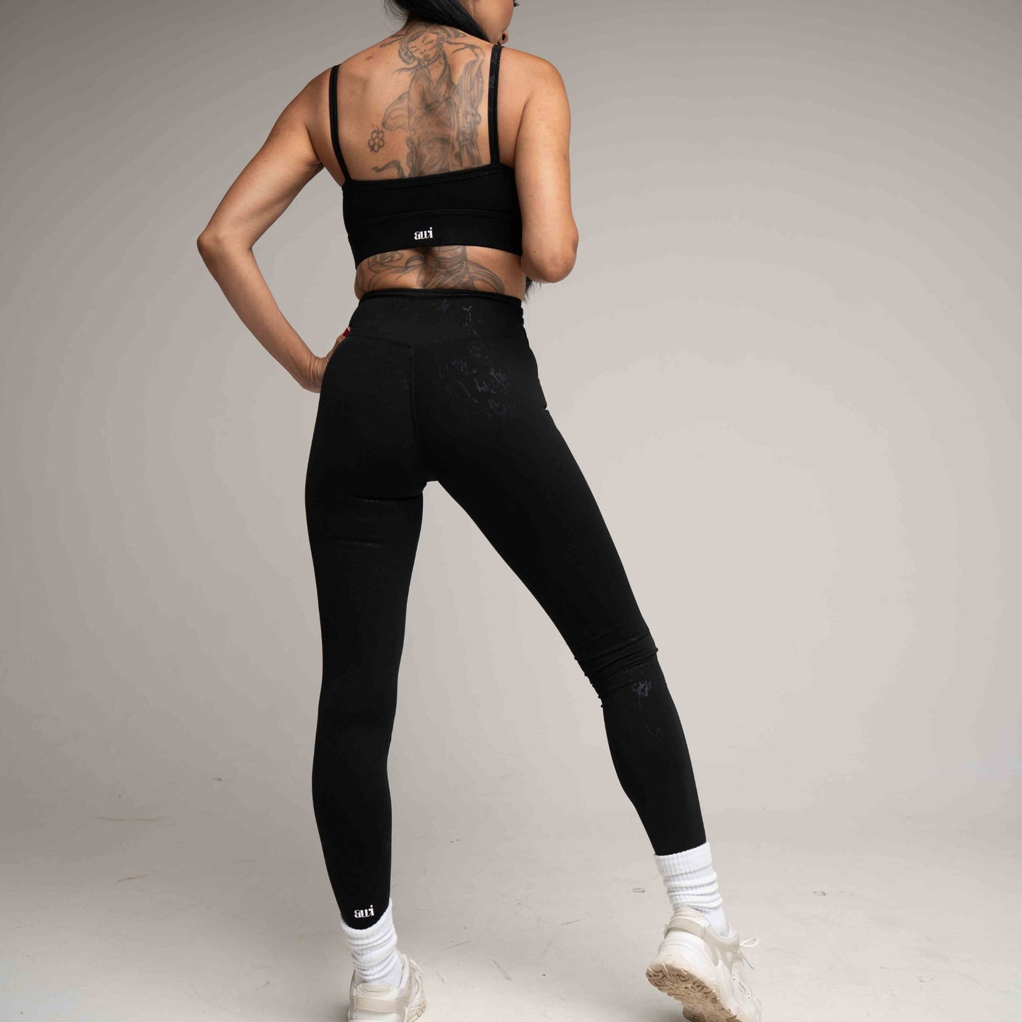 Person wearing black athletic leggings and sports bra on a plain background
