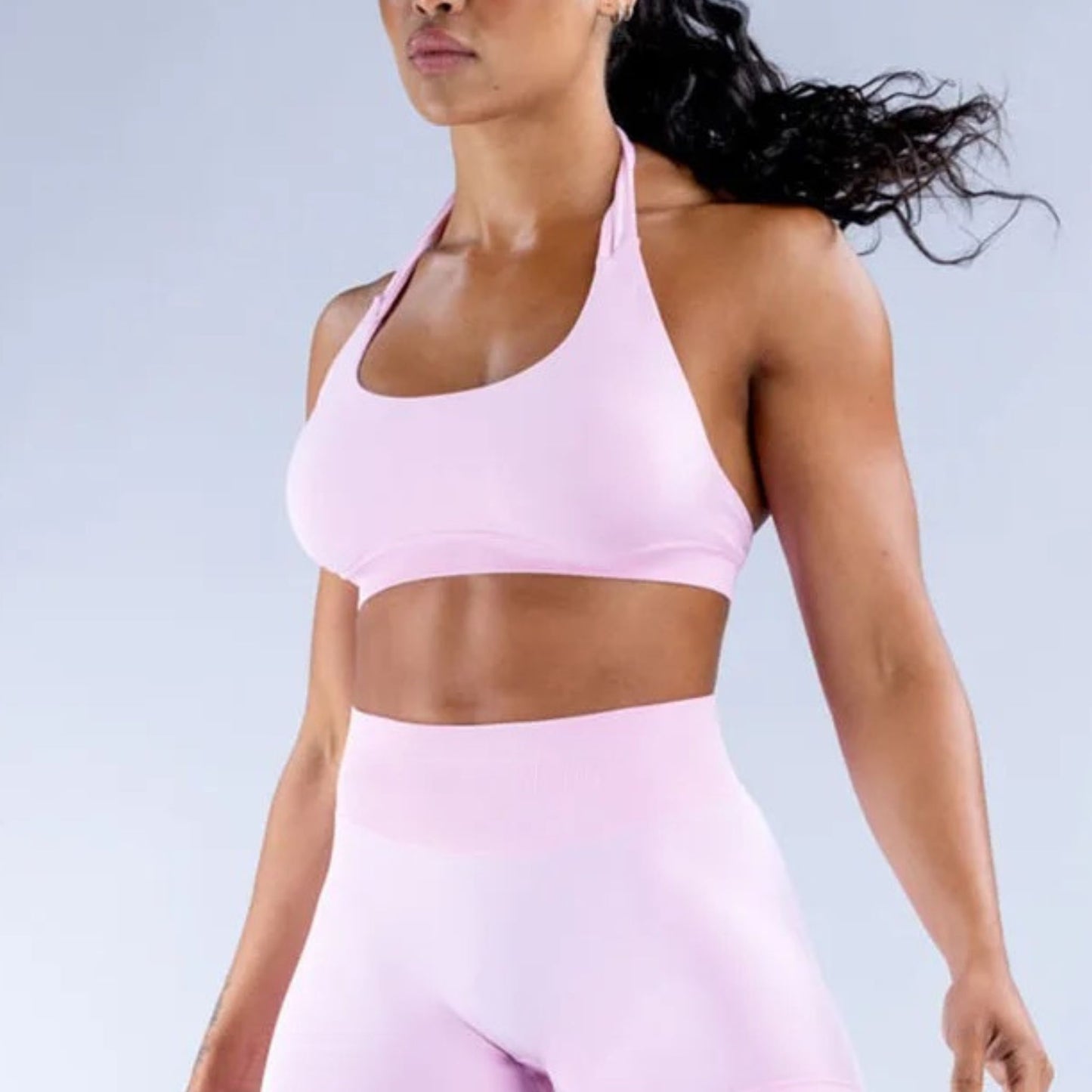 Woman wearing a pink halter top sports bra and seamless leggings