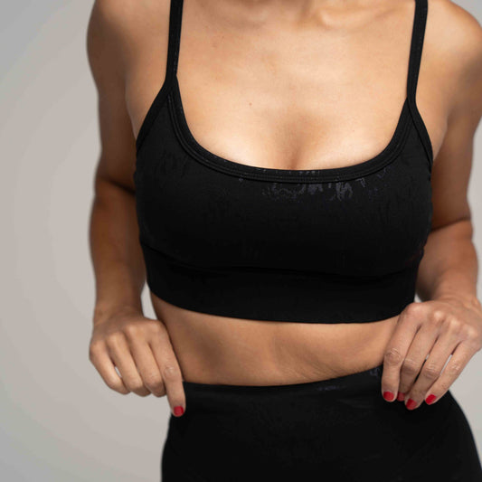 Person wearing a black sports bra against a neutral background