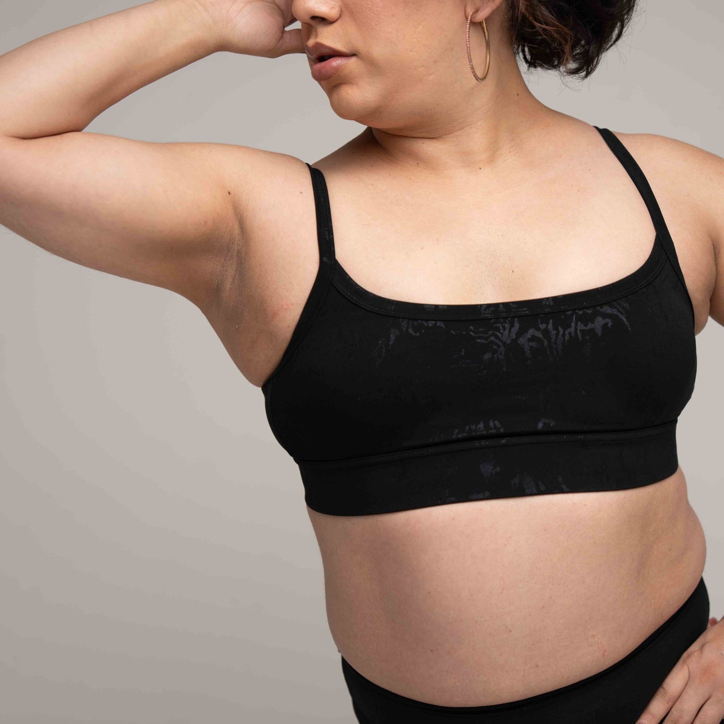 Person wearing a black sports bra against a neutral background