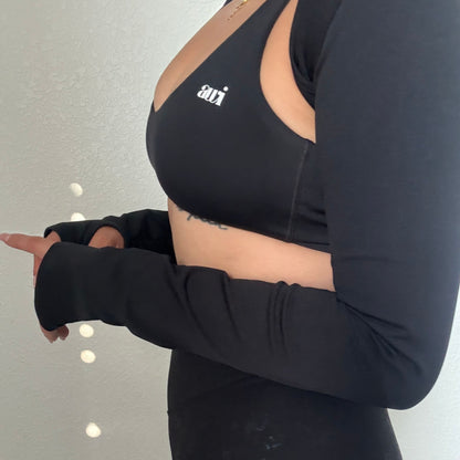 Person wearing a black long-sleeve top with a brand logo on a plain background