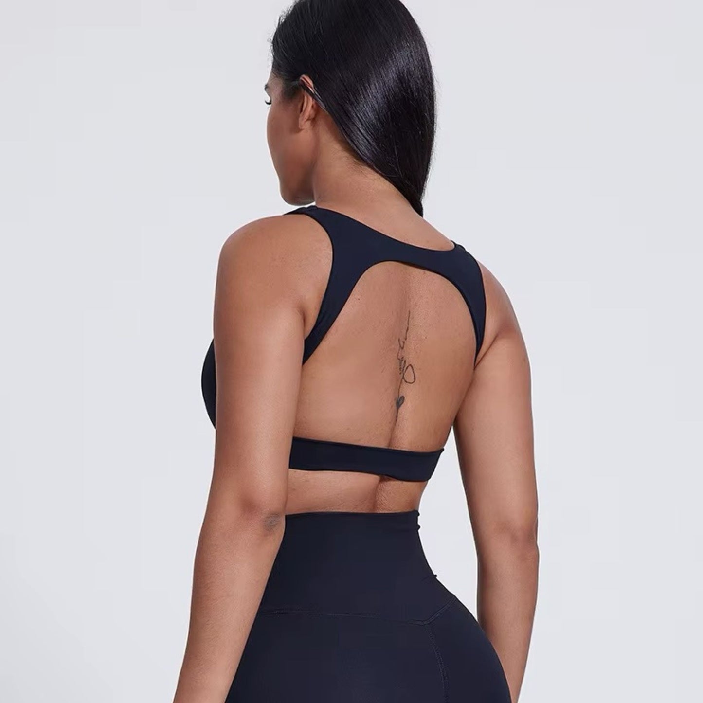 Model wearing black open-back bra with romantic minimal and seamless design by avvi