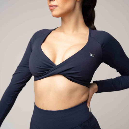Woman wearing a navy long-sleeve top with a brand logo on a neutral background