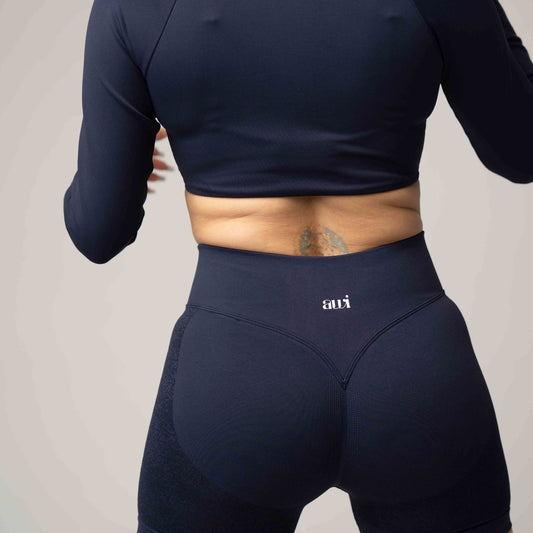 Person wearing navy athletic outfit with 'avi' brand logo on a plain background
