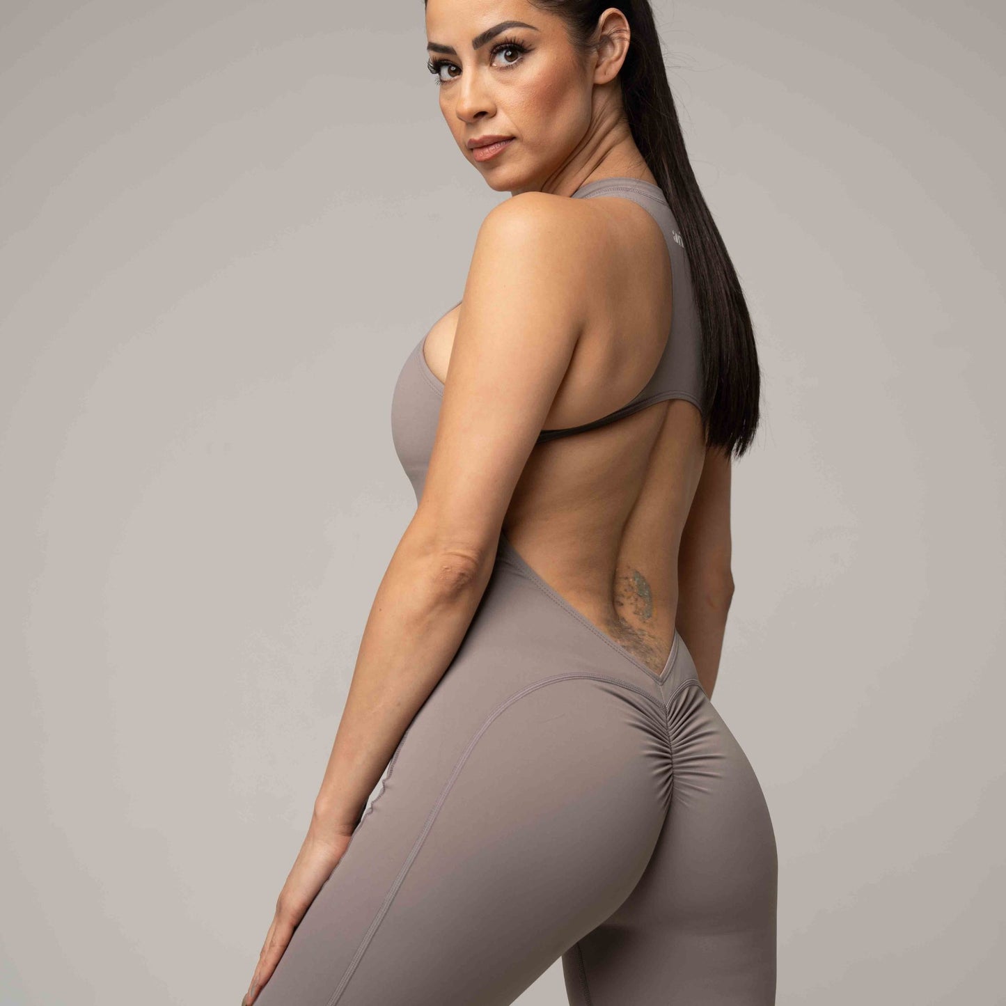 Woman wearing a gray athletic outfit on a plain background