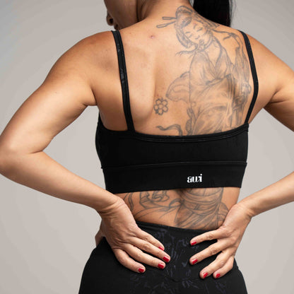 Person wearing a black sports bra with 'avi' branding on a plain background