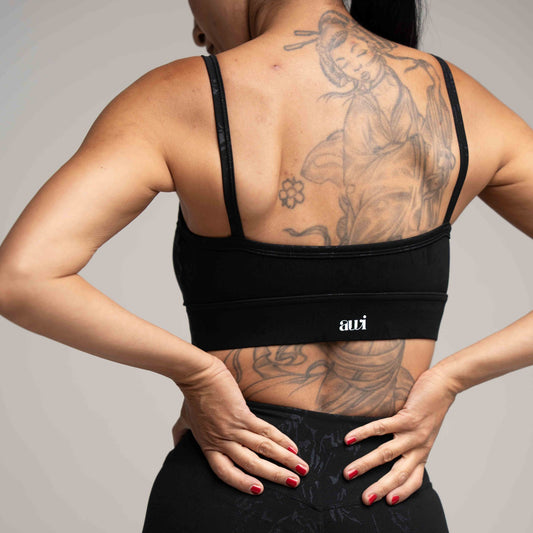 Person wearing a black sports bra with 'avi' branding on a plain background